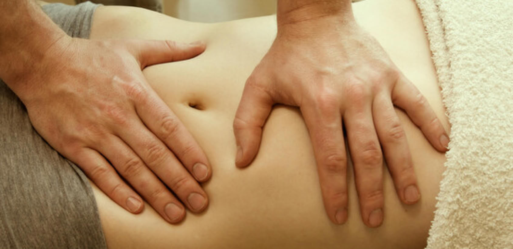 Massage chi nei tsang pratiqué avec des pressions douces sur l'abdomen d'une patiente