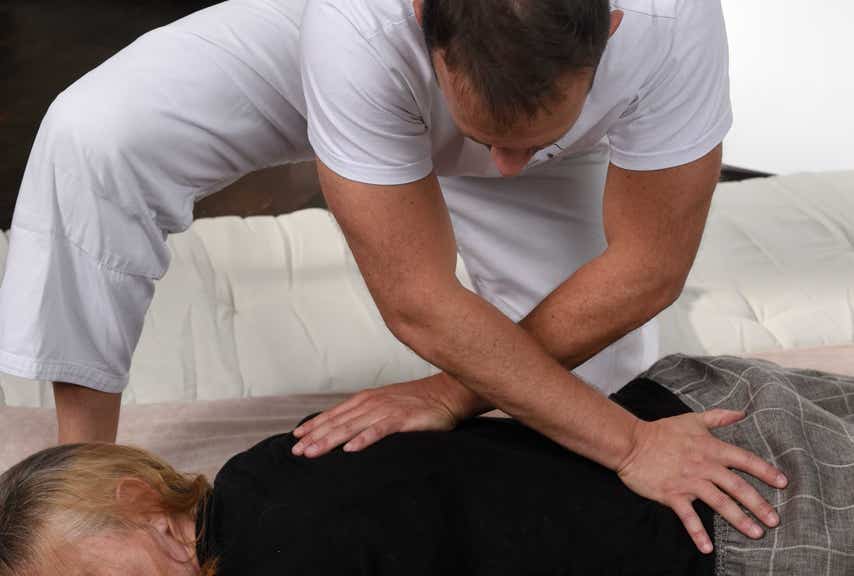 Jérôme Casadebaig pratiquant au sol un étirement bras croisés pour soulager les tensions du dos d'un patiente au cabinet terre de shiatsu Lyon 5e