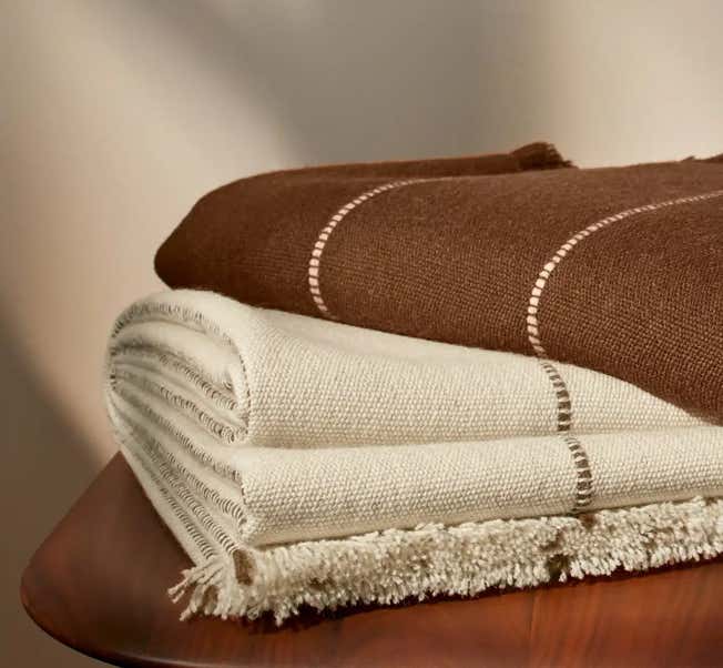 un plaid marron avec 2 rayures dorées posé en décalé sur un même plaid de couleur crème, illustrant la mise à disposition de matériel utiles aux soins holistiques au cabinet Terre de Shiatsu Lyon 5e
